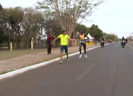 Preparador entregando garrafa com líquido vermelho ao atleta queniano na Corrida do Pantanal (Foto: Magno Lemos/Reprodução)